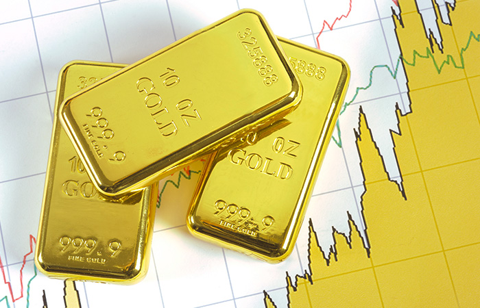 gold bars in front of a chart showing a price rally